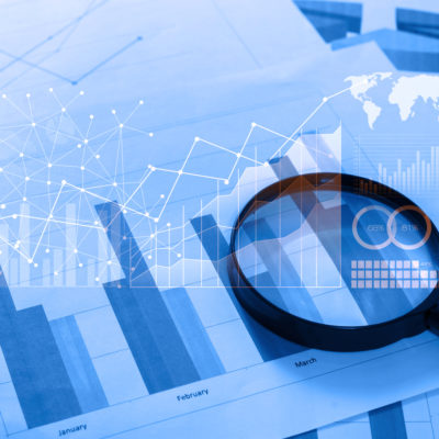 Magnifying glass and documents with analytics data lying on table,selective focusMagnifying glass and documents with analytics data lying on table,selective focus